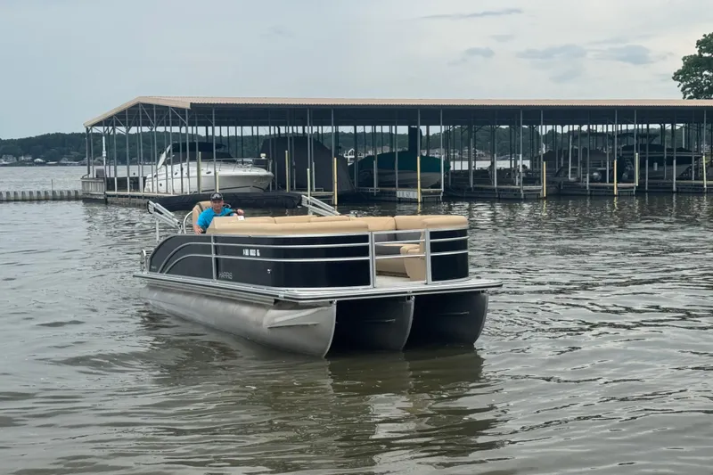 Slide: The Image of 2022 Harris Sunliner 250 pontoon boat on a lake near a marina. - 11