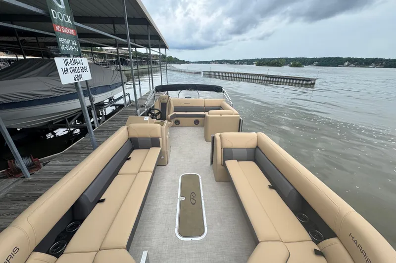Slide: The Image of 2022 Harris Sunliner 250 pontoon boat docked by a serene lake under cloudy skies. - 12