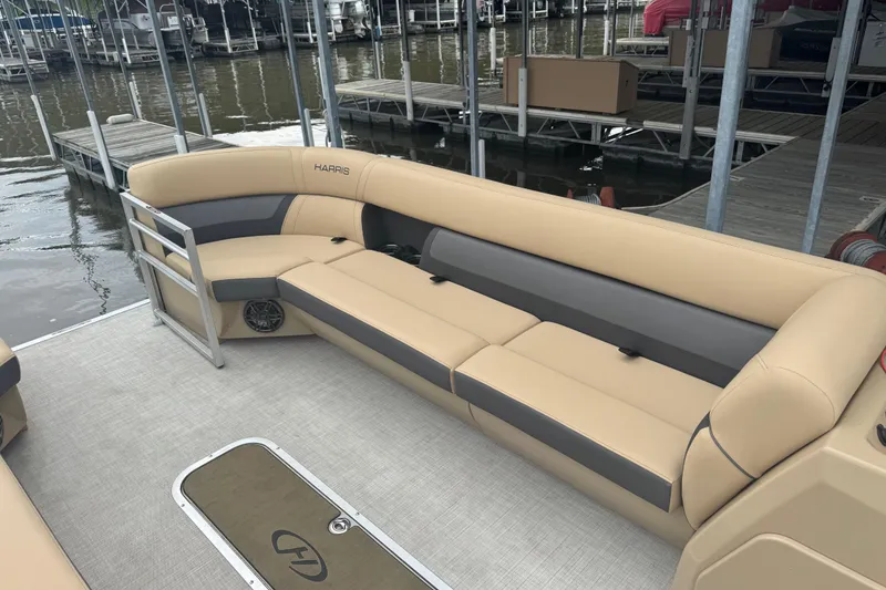 Slide: The Image of 2022 Harris Sunliner 250 pontoon boat with beige seating at a marina dock. - 14