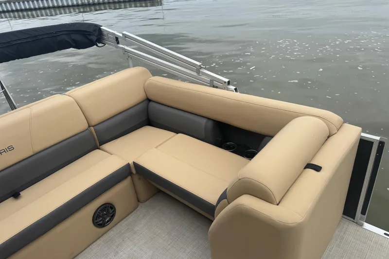 Slide: The Image of 2022 Harris Sunliner 250 boat interior with beige seating, cup holders, and water view. - 16