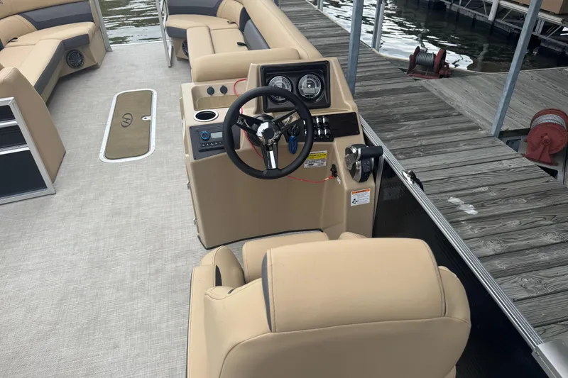 Slide: The Image of 2022 Harris Sunliner 250 boat interior with steering console and beige seating. - 24