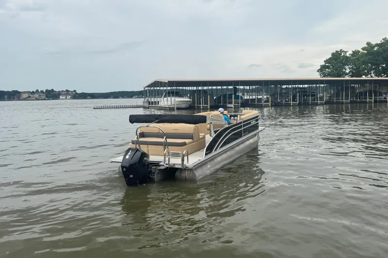 Slide: The Image of 2022 Harris Sunliner 250 pontoon boat on a calm lake near a marina. - 3