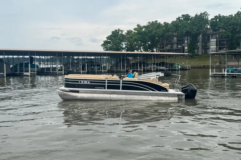 Slide: The Image of 2022 Harris Sunliner 250 pontoon boat on a calm lake near docks and trees. - 6