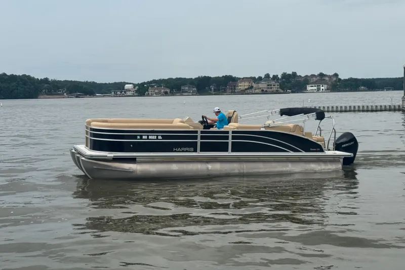 Slide: The Image of 2022 Harris Sunliner 250 pontoon boat on a calm lake with scenic background. - 7