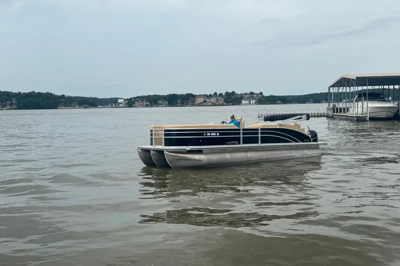 Slide: The Image of 2022 Harris Sunliner 250 pontoon boat on a calm lake near a dock. - 8