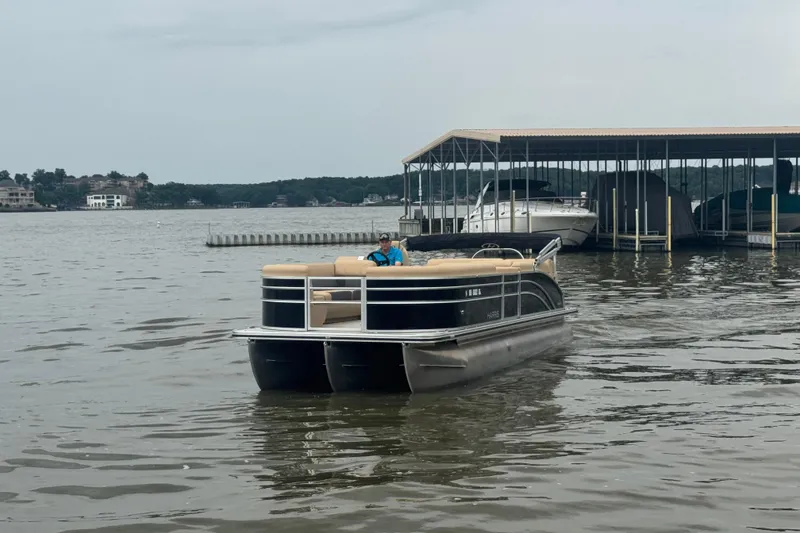 Slide: The Image of 2022 Harris Sunliner 250 pontoon boat on a lake near a marina. - 9