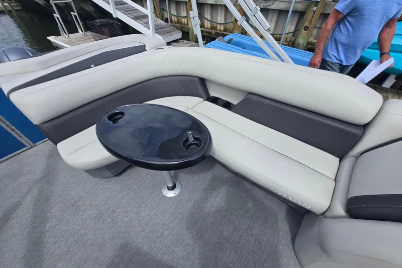 Slide: The Image of 2022 Sylvan 8522 Mirage Cruise boat interior with gray seating and a black table. - 5