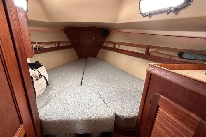 Slide: The Image of 1989 Island Packet 35 sailboat interior cabin with cozy V-berth and wooden accents. - 10