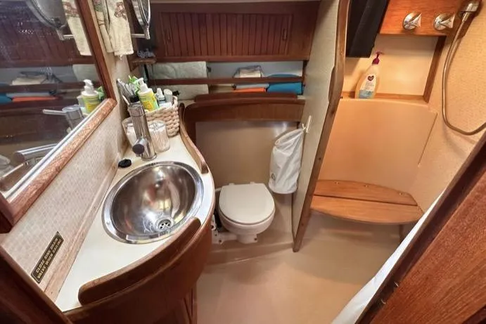 Slide: The Image of 1989 Island Packet 35 yacht bathroom with sink, toilet, and wooden accents. - 12