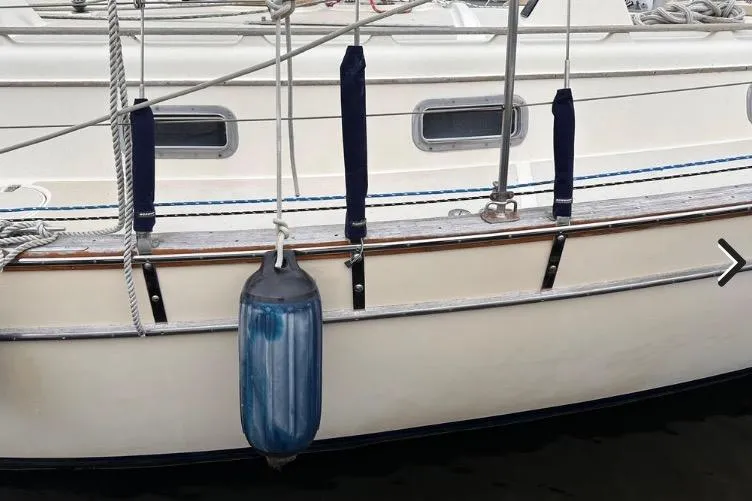 Slide: The Image of 1989 Island Packet 35 sailboat with blue fender and white hull detail. - 2