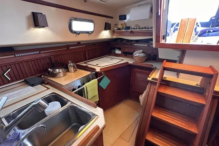 Slide: The Image of 1989 Island Packet 35 yacht interior kitchen with wooden cabinetry and stainless steel sink. - 9