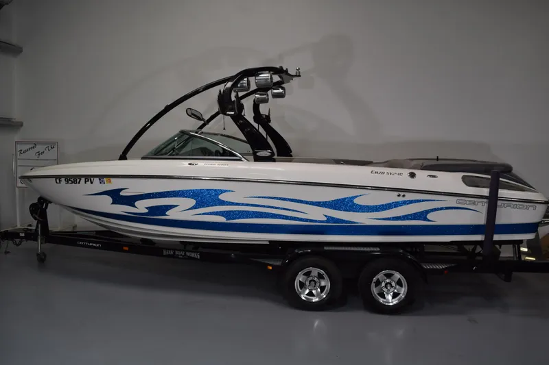 The Image of 2007 Centurion SV 240 boat with blue graphics on a trailer in a showroom. - 1