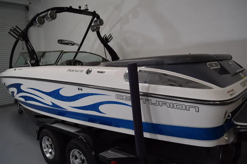 Slide: The Image of 2007 Centurion SV 240 boat with blue wave design, parked indoors on a trailer. - 6