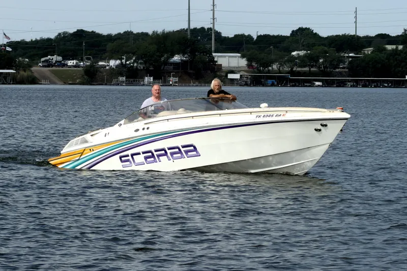 Slide: The Image of 1995 Wellcraft Scarab 31 boat cruising on a lake with two passengers onboard. - 18