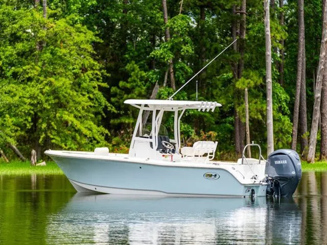 Slide: The Image of 2026 Sea Hunt Ultra 229 boat on calm water near forest. - 5