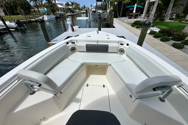 Slide: The Image of 2021 Cobia 240 Center Console boat interior with white seating at a marina. - 20