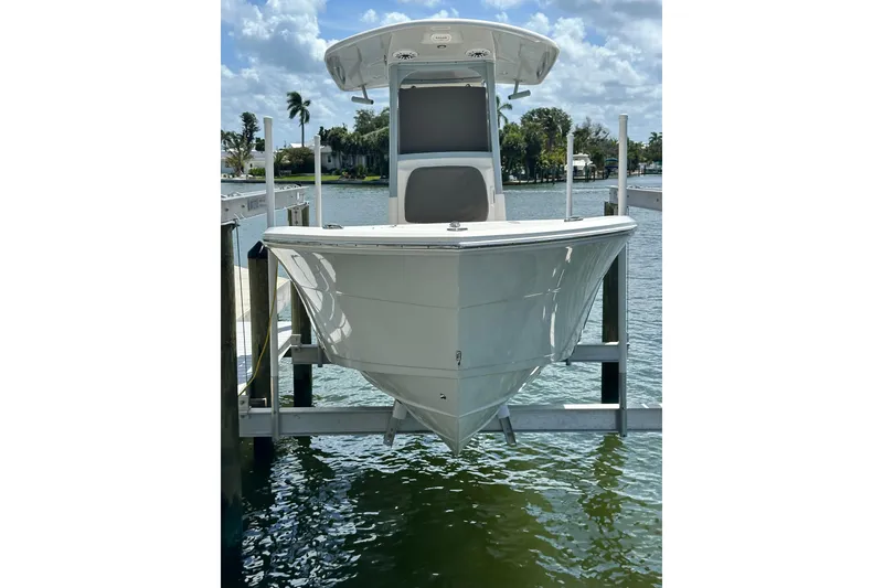 Slide: The Image of 2021 Cobia 240 Center Console boat on lift, docked by waterfront under blue sky. - 3
