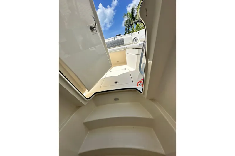 Slide: The Image of 2021 Cobia 240 Center Console interior view with open hatch, steps, and clear sky. - 38