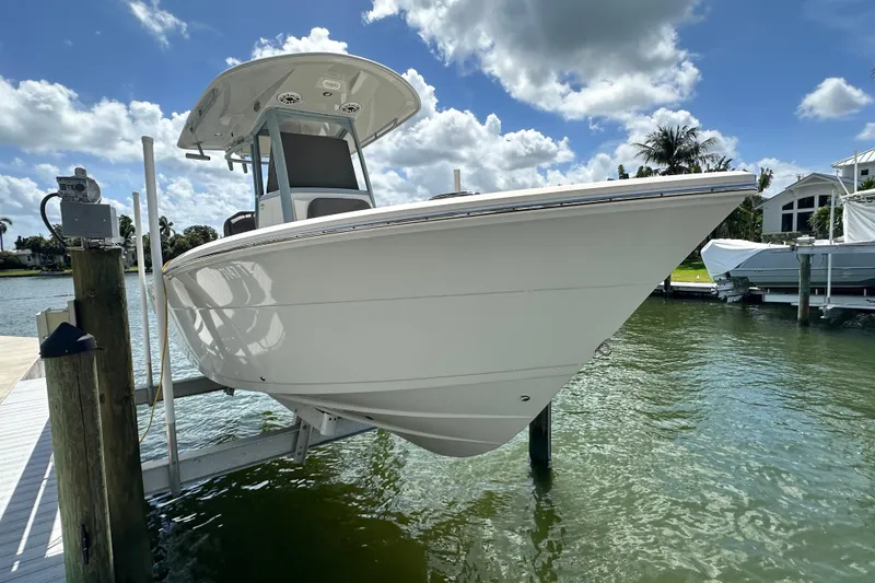 Slide: The Image of 2021 Cobia 240 Center Console boat docked on a lift under a sunny sky. - 4