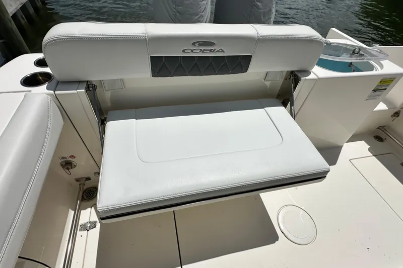 Slide: The Image of 2021 Cobia 240 Center Console boat seat with white upholstery and cup holders. - 42