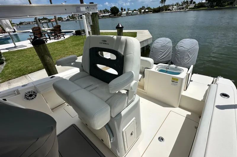 Slide: The Image of 2021 Cobia 240 Center Console boat with dual engines, docked by a scenic waterfront. - 50