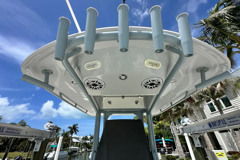 Slide: The Image of 2021 Cobia 240 Center Console boat with rod holders and speakers, docked under a clear blue sky. - 54