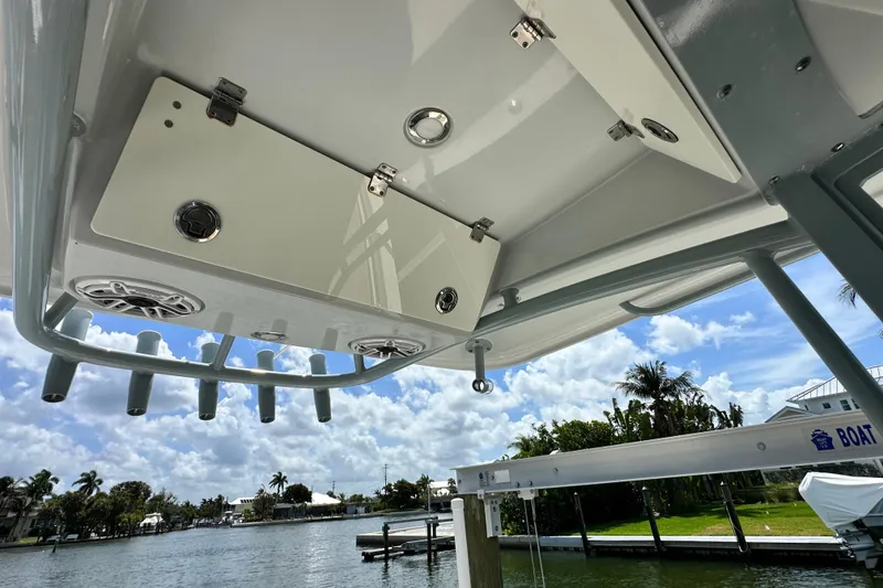 Slide: The Image of 2021 Cobia 240 Center Console boat with rod holders and speakers, docked by a scenic waterfront. - 55