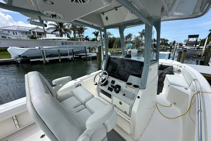 Slide: The Image of 2021 Cobia 240 Center Console boat interior with helm, docked near waterfront homes. - 60