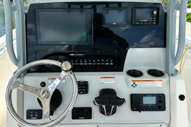 Slide: The Image of Center console of 2021 Cobia 240, featuring steering wheel, Garmin display, and control panel. - 65