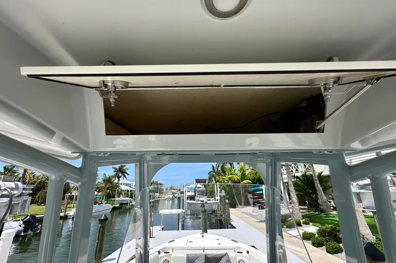 Slide: The Image of 2021 Cobia 240 Center Console boat with open overhead compartment, docked near palm trees. - 77
