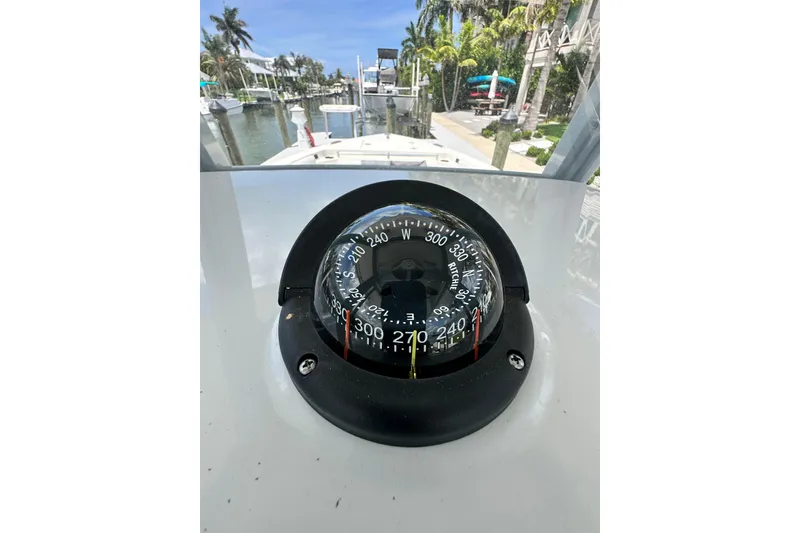 Slide: The Image of Compass on 2021 Cobia 240 Center Console boat, docked near palm trees and waterway. - 78