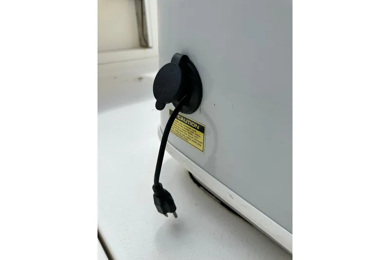 Slide: The Image of Power outlet on 2021 Cobia 240 Center Console boat with caution label. - 80