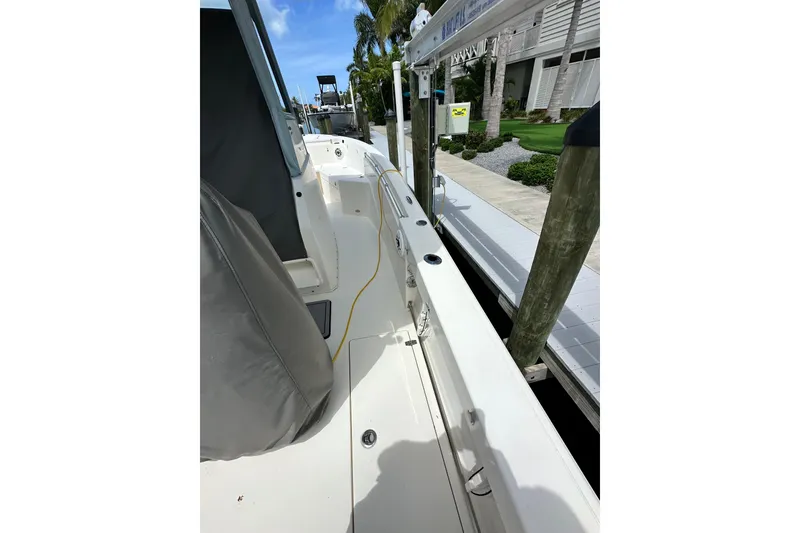 Slide: The Image of 2021 Cobia 240 Center Console boat docked, showcasing side deck and seating area. - 86