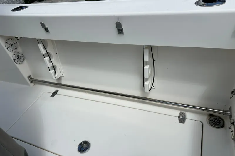 Slide: The Image of 2021 Cobia 240 Center Console boat storage compartment with rod holders and drainage system. - 91