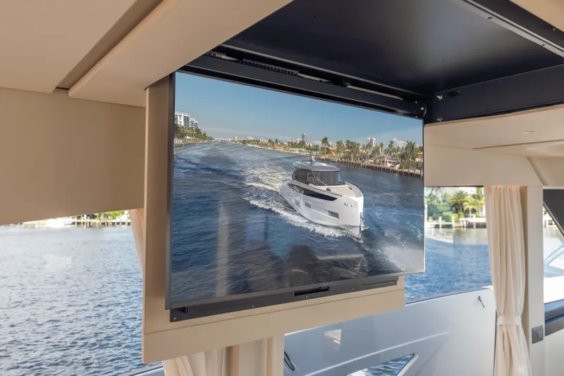 Slide: The Image of Interior view of 2025 Azimut Seadeck 6 yacht with a screen displaying a cruising scene. - 12