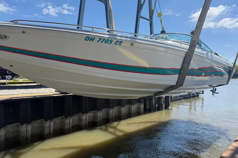 Slide: The Image of 1999 Formula 312 FASTech boat lifted from water, showcasing sleek design and vibrant stripes. - 25