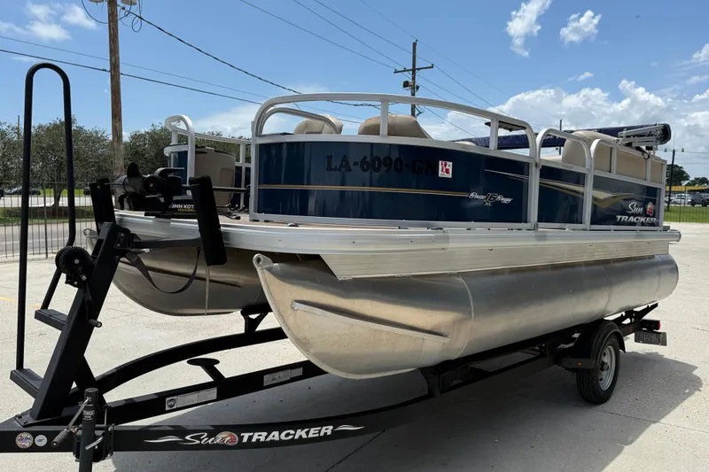 Slide: The Image of 2022 Sun Tracker Bass Buggy 16 DLX pontoon boat on trailer, parked outdoors. - 2