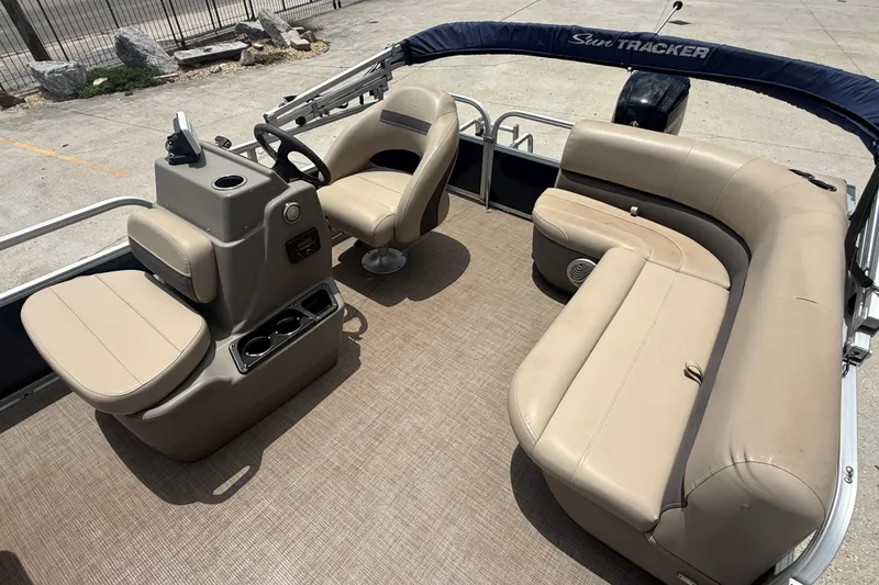 Slide: The Image of 2022 Sun Tracker Bass Buggy 16 DLX pontoon boat interior with beige seating and steering console. - 7