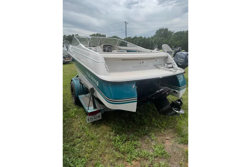 Slide: The Image of 1994 Four Winns 200 Horizon boat on trailer, parked on grass under cloudy sky. - 3
