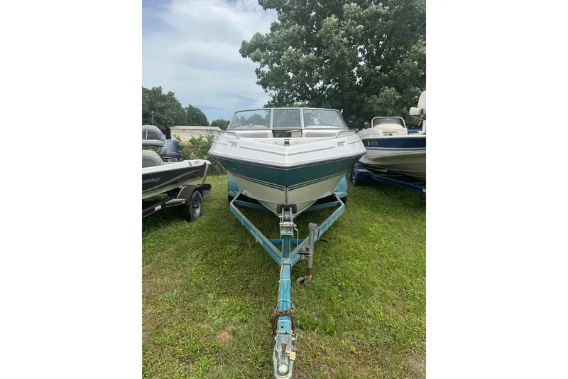 Slide: The Image of 1994 Four Winns 200 Horizon boat on trailer, parked on grass, surrounded by trees. - 4