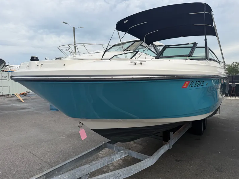 Slide: The Image of A blue and white Sea Ray SPX 230 Outboard on a trailer on land. - 0