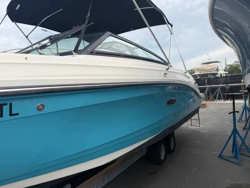 Slide: The Image of A blue and white Sea Ray SPX 230 Outboard on a trailer on land. - 3