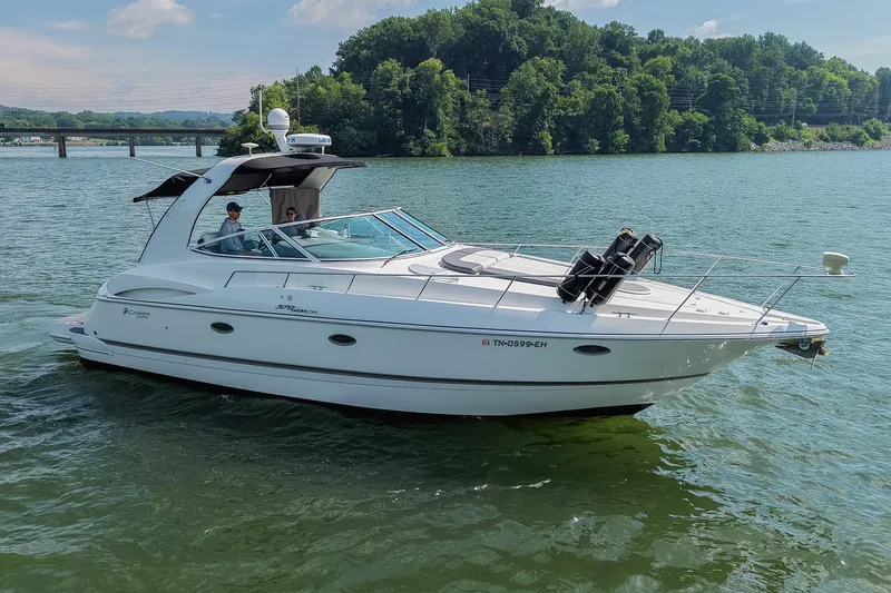 Slide: The Image of 2005 Cruisers Yachts 370 Express on a serene lake with lush green shoreline. - 12