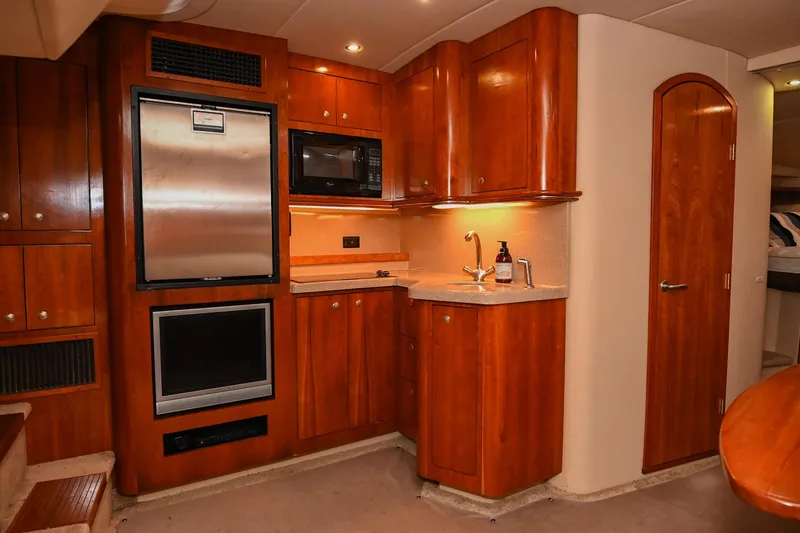 Slide: The Image of 2005 Cruisers Yachts 370 Express kitchen with wood cabinetry, stainless appliances, and modern fixtures. - 31