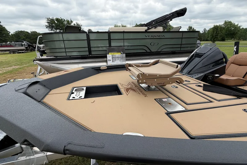 Slide: The Image of 2026 Xpress H18 Bass boat with tan deck and seating, displayed outdoors. - 2