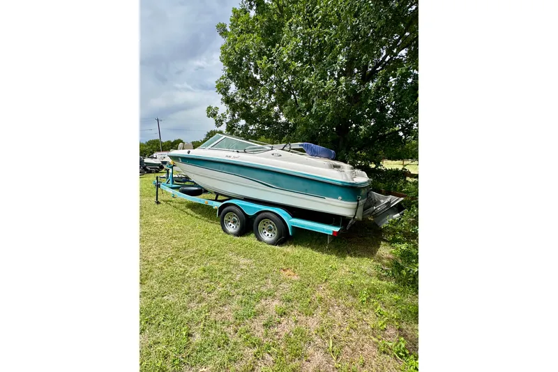 Slide: The Image of Chaparral 1930 SS boat from 1994 on a trailer, parked on grass near trees. - 2