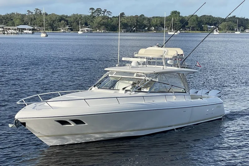 The Image of 2009 Intrepid 430 Sport Yacht cruising on a serene lake with lush green shoreline. - 0