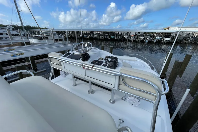 Slide: The Image of 2009 Intrepid 430 Sport Yacht helm with marina view, featuring steering wheel and controls. - 16