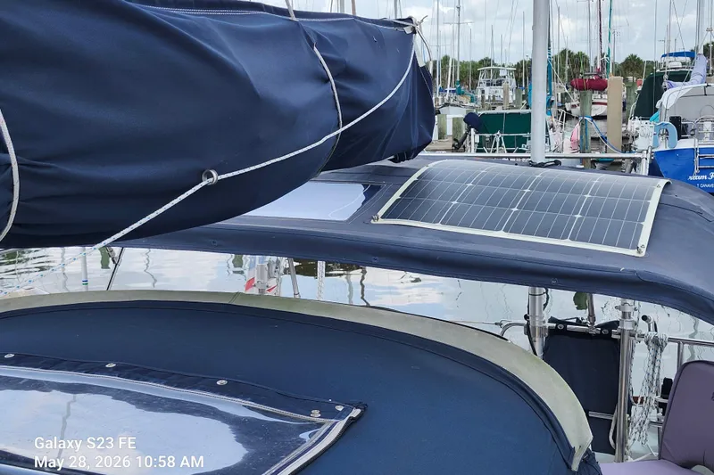 Slide: The Image of Sailboat with solar panel, Freedom 35 model, docked at marina, blue canvas cover. - 31