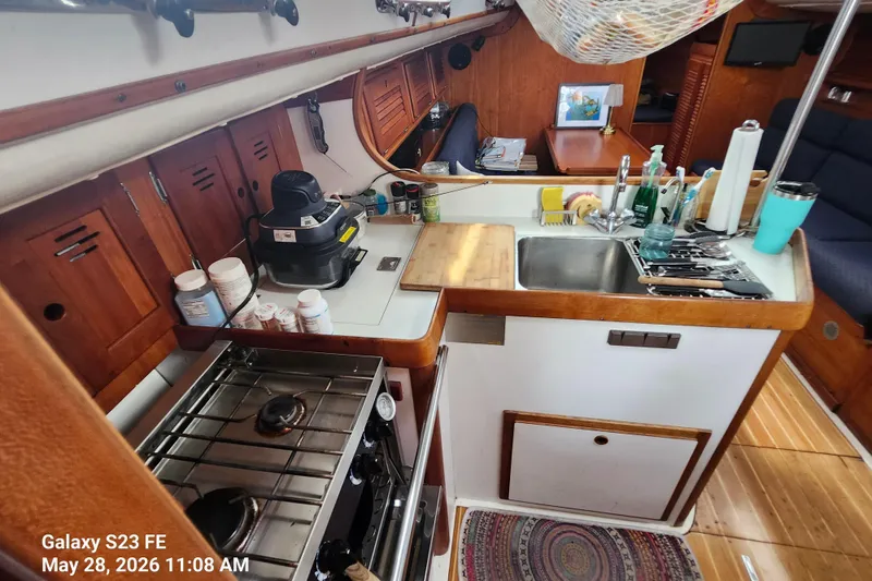 Slide: The Image of Compact kitchen in a 1995 Freedom 35 sailboat with stove, sink, and wooden cabinetry. - 8